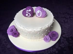 Feesttaarten - Witte taart gecappitoneerd met paarse 3D harten en roosjes